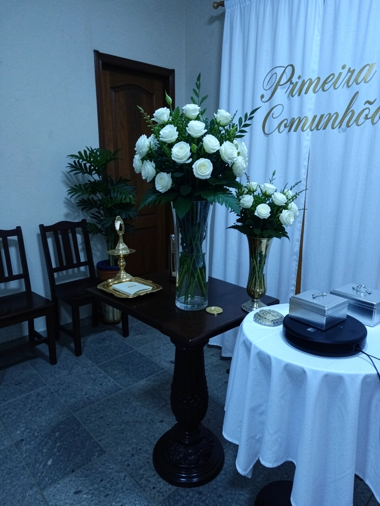 Vaso com flores da estação e folhagens verdes sobre uma mesa de madeira.