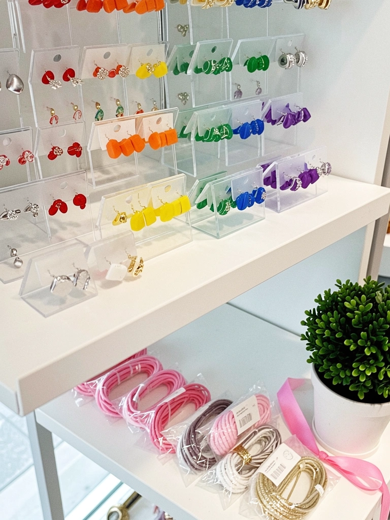 Vitrine com bijuterias organizadas por cores em gradiente de arco-íris.