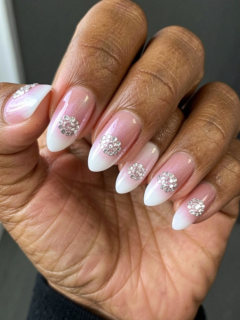 Mão feminina com unhas em degradê nude para branco, estilo baby boomer, sobre fundo neutro.