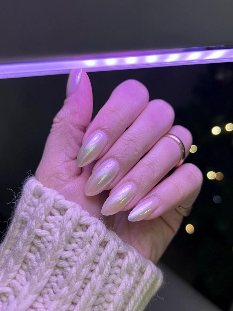 Mão com unhas pintadas sob luz UV/LED de aparelho de secagem.