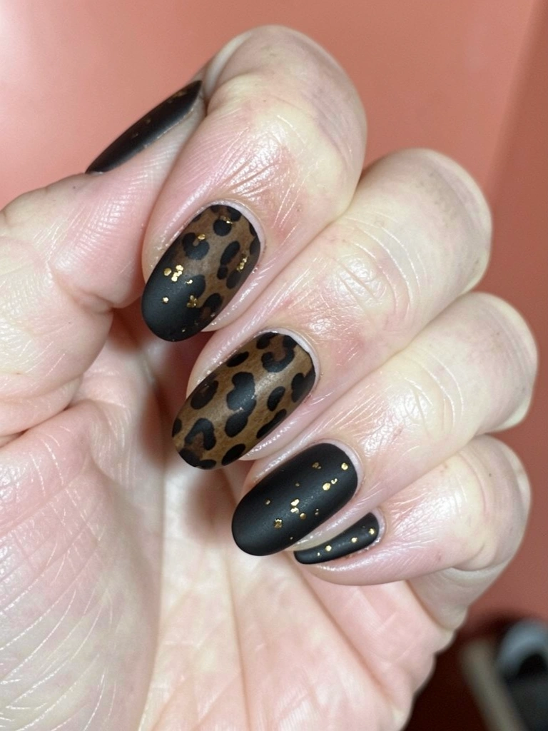 Unhas pintadas com esmalte fosco escuro e detalhes metálicos prateados em formato de meia-lua.