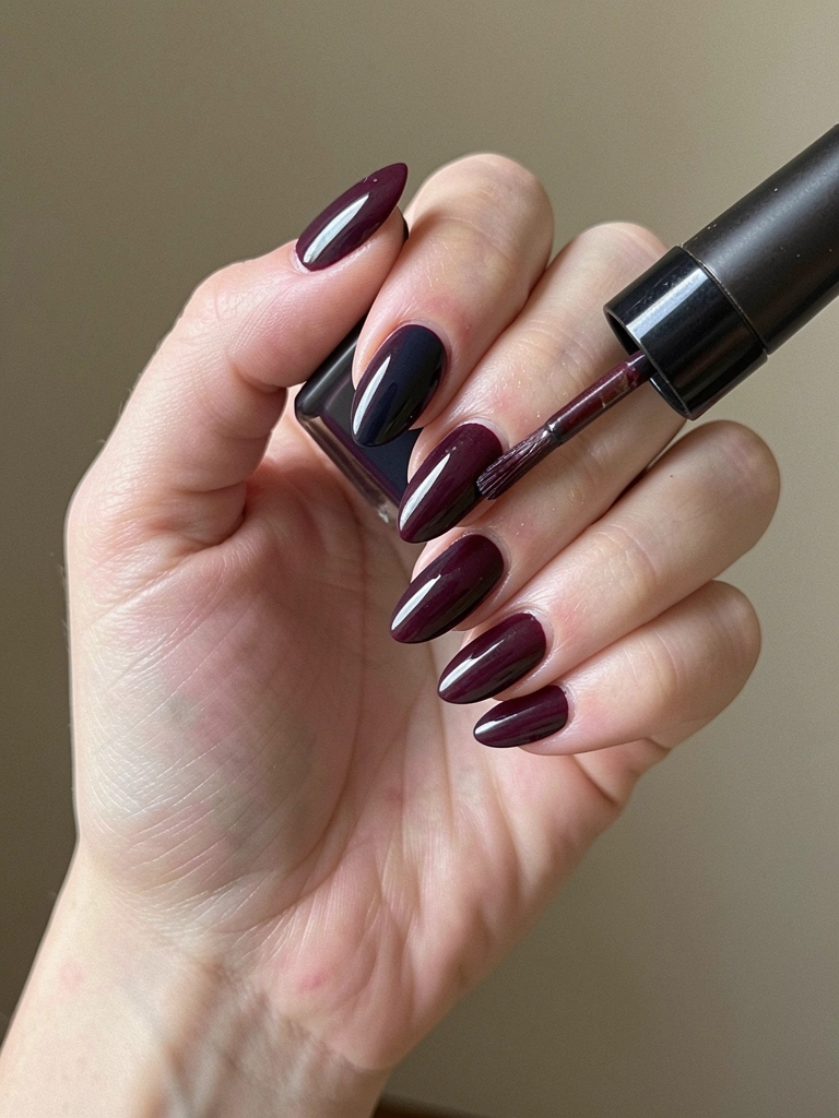 Mão aplicando pincel com esmalte fosco sobre unha colorida
