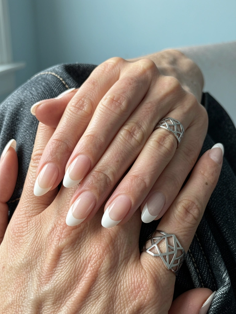 Unhas de gel branco perolado com francesinha invertida, detalhe em fio metálico prateado.